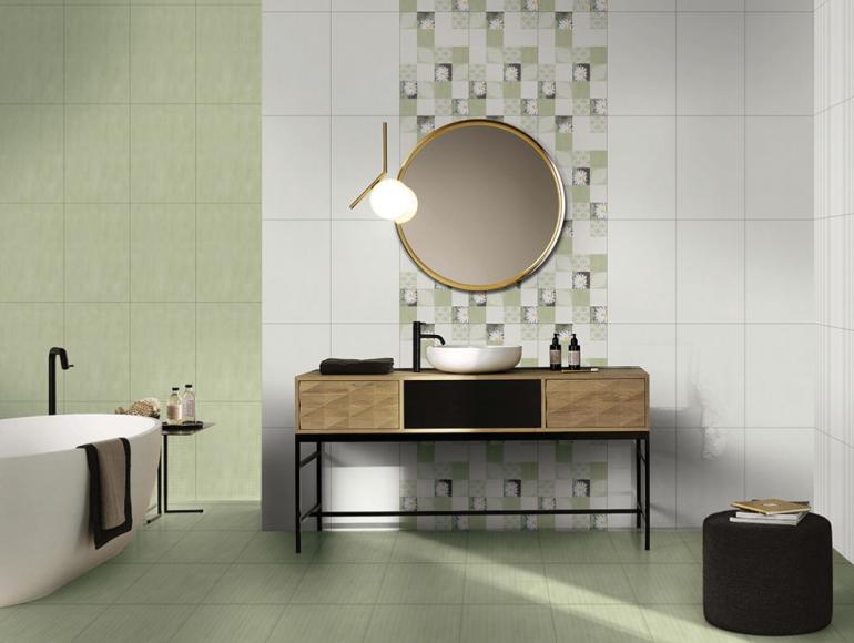 Modern green bathroom design with stylish tiles, floating vanity, round mirror, and elegant bathtub setup.